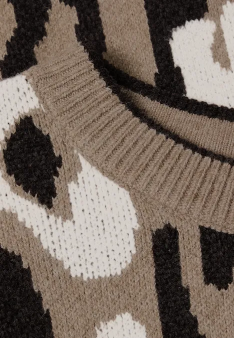 Close-up van een gebreide trui met abstract motief in beige, wit en zwart.