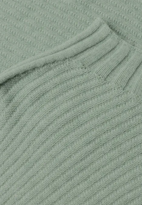Detail eines hellgrünen, grob gestrickten Pullovers