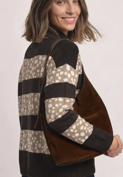 Vrouw met een bruin suède tas en een gemêleerde trui, die over haar schouder kijkt.