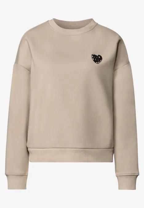 Loose Fit Sweatshirt mit Patch Detail clay sand Beiges, schlichtes Sweatshirt mit Rundhalsausschnitt und kleinem schwarzen Herz-Emblem auf der Brust.