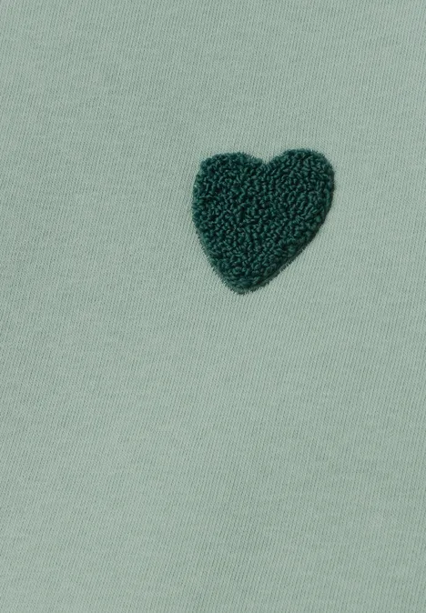 Loose Fit Sweatshirt mit Patch Detail eucalyptus green Ein dunkles grünes Herz aus Plüsch auf mintgrünem Stoff.