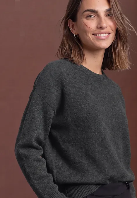 Pullover in Unifarbe mit Rundhals armor grey mel. Eine lächelnde Frau in grauem Pullover vor braunem Hintergrund.
