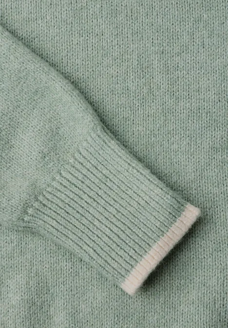Nahaufnahme eines mintgrünen Strickpullover-Ärmels mit Rippbündchen.
