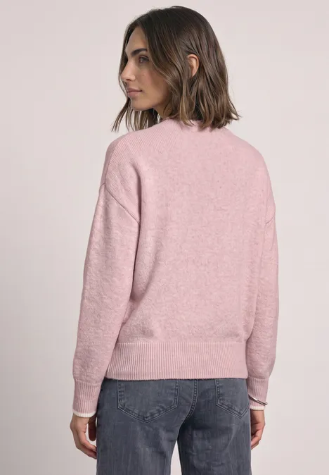 Frau von hinten in rosafarbenem Pullover und dunkler Jeans