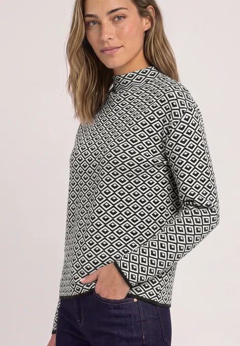 Pullover mit Turtle Neck und Jacquardmuster Black Frau mit schwarz-weißem Rautenmuster-Pullover, lässig mit einer Hand in der Hosentasche.