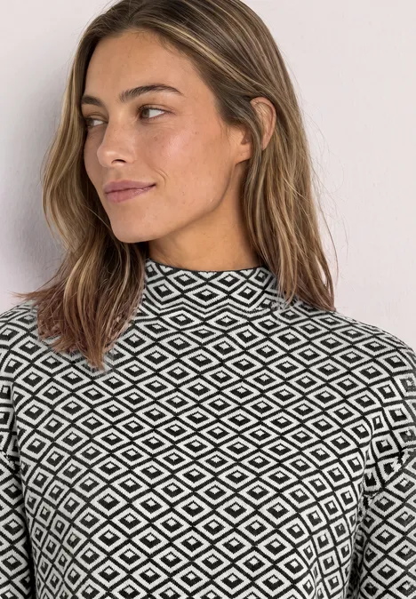 Pullover mit Turtle Neck und Jacquardmuster Black Eine Frau mit gemustertem Rollkragenpullover, schwarz-weißem Rautenmuster, schaut zur Seite