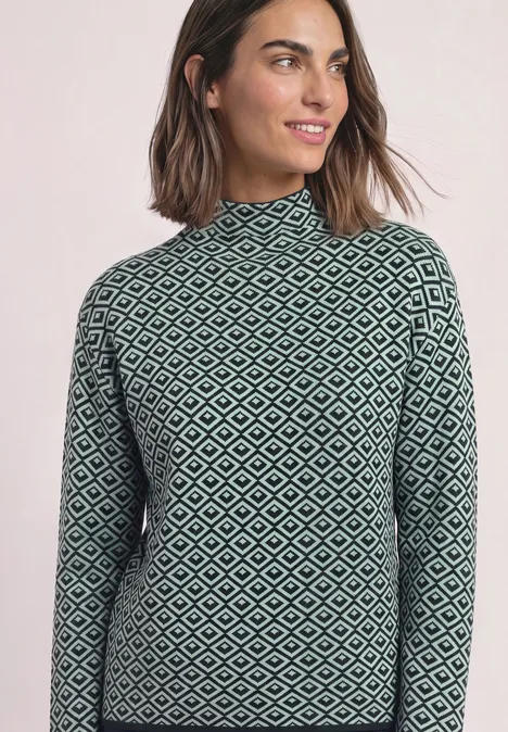 Pullover mit Turtle Neck und Jacquardmuster stormy green Frau mit schulterlangem Haar trägt hochgeschlossenes, langärmeliges Oberteil mit grün-schwarzem Rautenmuster.