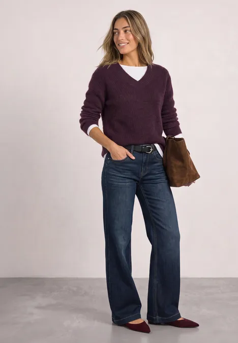 Trui van veergaren met V-hals berry plum Vrouw met paarse trui, wijd jeans, bordeaux ballerina's en clutch.