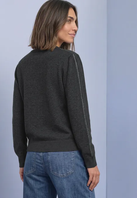 Femme en sweat gris foncé et jean, vue de dos, regard tourné sur le côté.