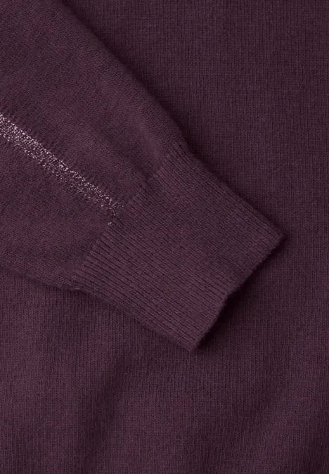 Gros plan sur le poignet d'un pull en maille bordeaux