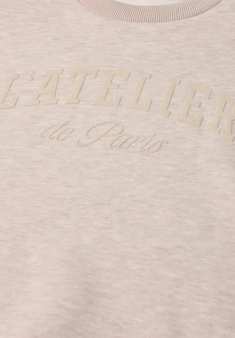 Beige-rosafarbener Pullover mit aufgesticktem Schriftzug 'L'ATELIER de Paris' auf der Brust.