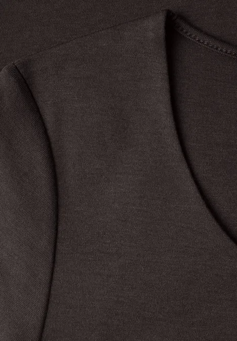 Close-up van een donkerbruin T-shirt met V-hals en zichtbare schoudernaad.