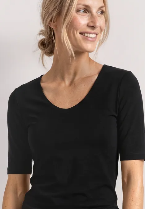T-shirt met V-hals Black Vrouw met blond haar in een knot, draagt een zwart T-shirt met halflange mouwen tegen een witte achtergrond.