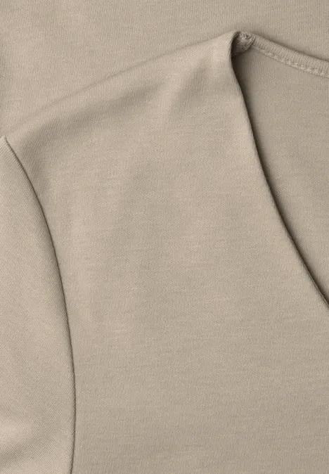 Nahaufnahme eines beigen T-Shirts mit sichtbarer Naht am Ausschnitt.