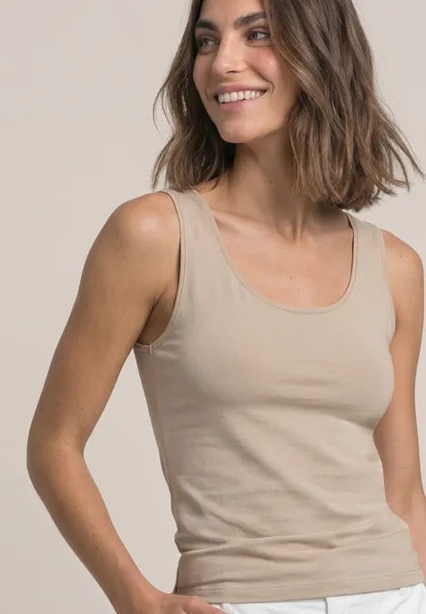 Basic Top mit Rundhals in Unifarbe clay sand Frau lächelt in beige Tanktop vor neutralem Hintergrund