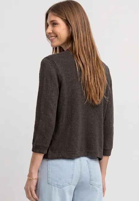 Eine Frau von hinten in brauner Jacke und hellblauen Jeans.