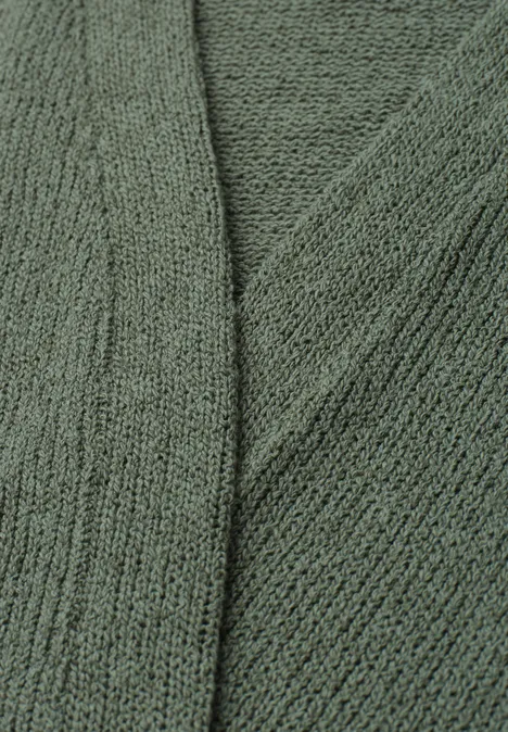 Close-up van een groen gebreide stof met een fijn steekpatroon en zachte textuur.