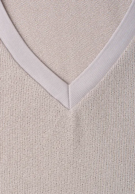 Nahe Aufnahme eines beigen Strickpullovers mit V-Ausschnitt.