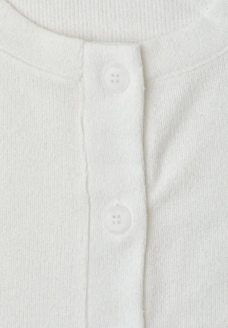 Nahaufnahme eines weißen T-Shirts mit Knopfleiste und zwei weißen Knöpfen.