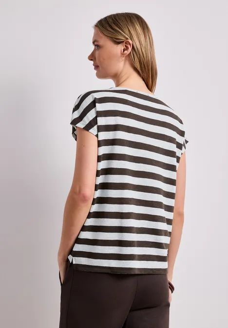 Vrouw van achteren in een gestreept T-shirt en bruine broek.