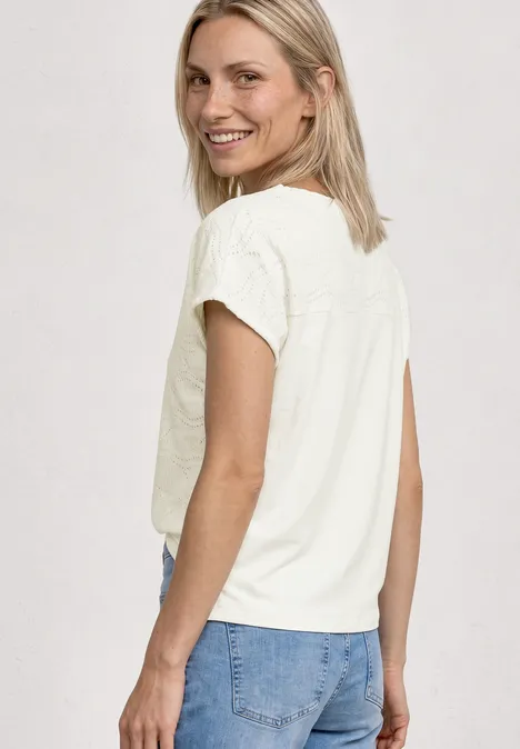 Frau mit weißem T-Shirt und blauer Jeans, von hinten, schulterlanges blondes Haar, neutraler Hintergrund.