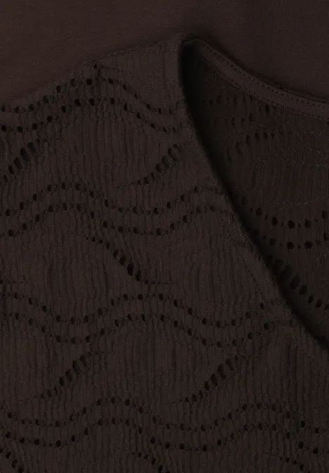 Nahaufnahme eines dunkelbraunen, gestrickten Textils mit wellenförmigem Lochmuster.