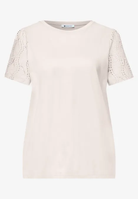 Ein schlichtes cremefarbenes T-Shirt mit kurzen Spitzenärmeln.