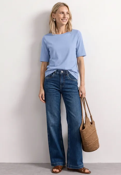 Basic T-Shirt mit U-Boot-Ausschnitt northern blue Frau trägt hellblaues T-Shirt, weite Jeans und hält eine geflochtene Strohtasche.