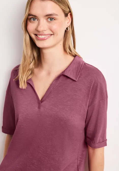 Person mit verschwommenem Gesicht trägt kurzärmliges rosa Poloshirt mit Kragen.