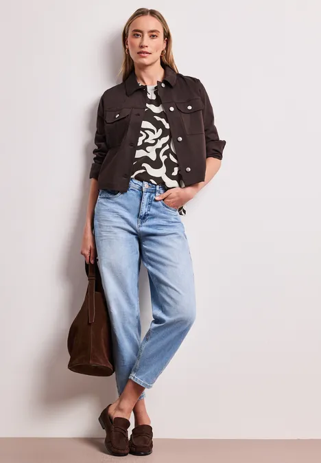 Veste en jean noire, top zébré, jean clair, mocassins noirs et sac marron.