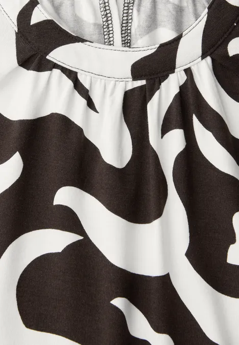 Vêtement noir et blanc à motif zèbre abstrait, avec une fermeture éclair apparente.