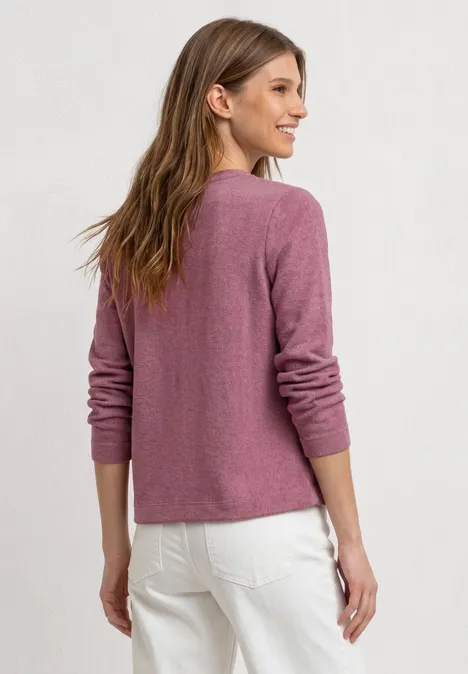 Veste à manches longues en look tricot dark clouded blush Jeune femme de dos portant un pull rose et un pantalon blanc sur un fond clair.
