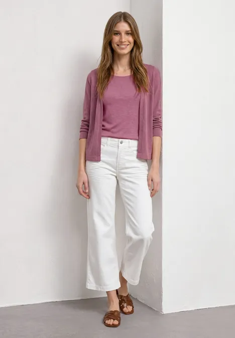 Veste à manches longues en look tricot dark clouded blush Femme en pull rose, jean culotte blanc et sandales marron, posant devant un mur blanc.
