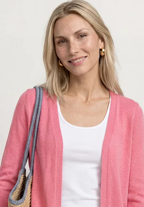 Veste à manches longues en look tricot blush berry Femme en t-shirt blanc et gilet rose, portant un sac, posant devant un fond neutre.