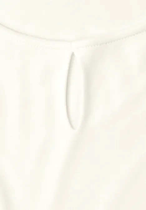 Witte blouse met een kleine ovale uitsparing bij de ronde halslijn.