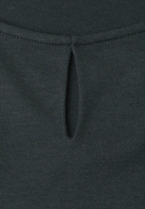 Close-up van een zwarte top met een druppelvormige uitsnijding en een plooi onder de halslijn.