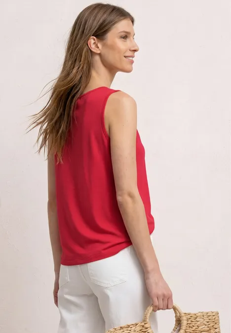 Top mit V-Neck und Knotendetail salsa red Frau von hinten in rotem ärmellosem Top, weißen Hosen und Strohtasche.