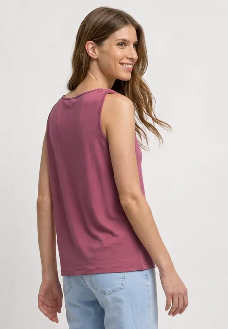 Top mit V-Neck und Knotendetail dark clouded blush Frau von hinten in ärmellosem, dunkelrotem Top und hellblauen Jeans mit lockerem Sitz und langen Haaren.