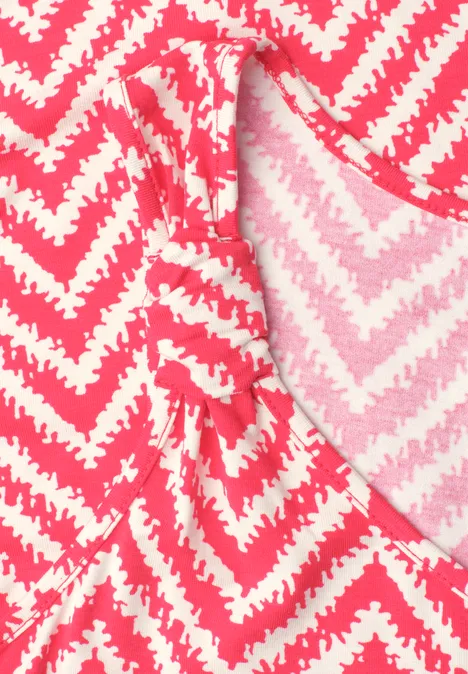Top avec col en V et détail de nœuds salsa red Gros plan d'un tissu rose et blanc à motif zigzag sur un vêtement