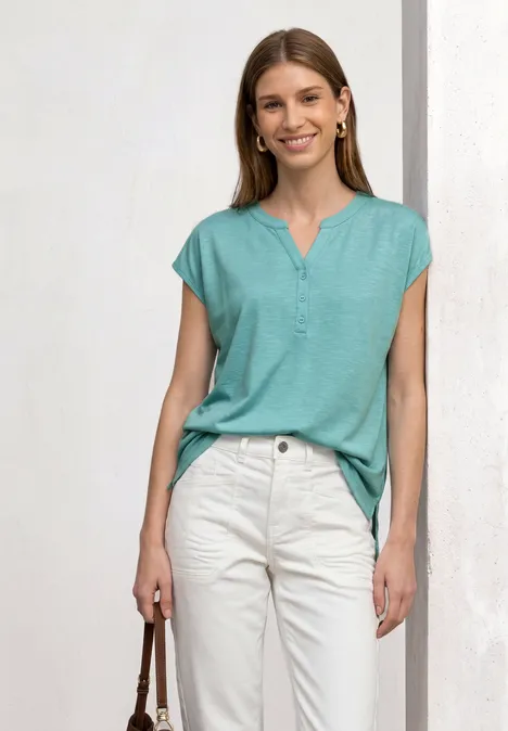 Dropped Shoulder Shirt mit Split Neck misty mint Frau in mintfarbenem V-Neck-Shirt und weißen Chino-Hosen hält eine braune Handtasche.