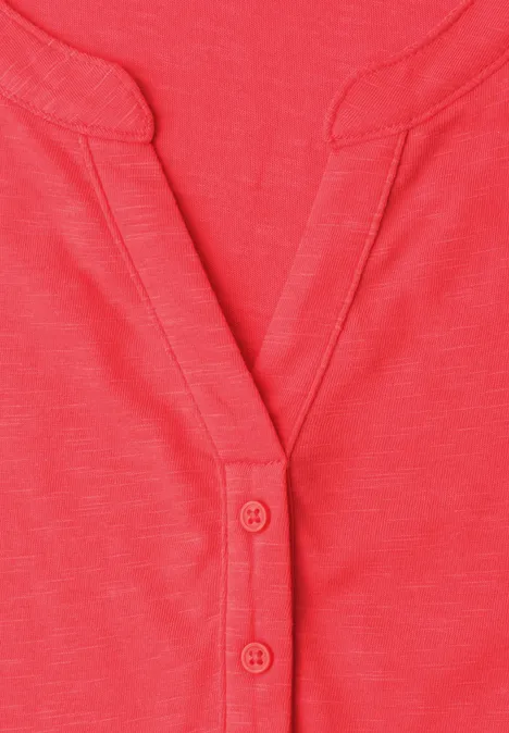Rotes Shirt mit V-Ausschnitt und zwei Knöpfen an der Leiste.