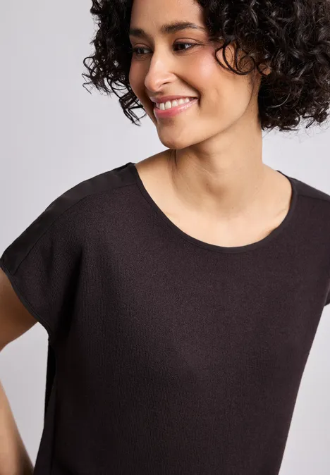Shirt met boothals en schouderdetails espresso brown Een vrouw met korte krullen en zwart shirt lacht schuin.
