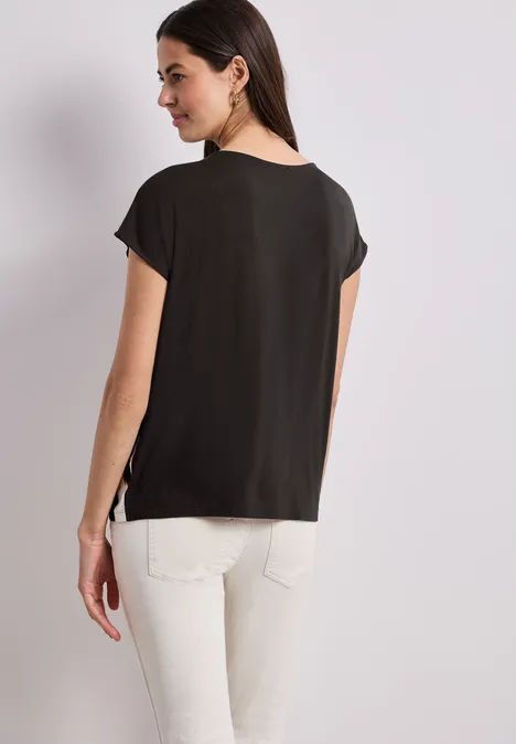 Frau von hinten, schwarze Kurzarmbluse, weiße Hose.