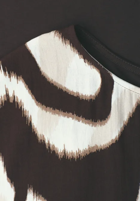 Nahaufnahme eines Stoffmusters mit unregelmäßigen braun-beigen Streifen auf hellem Grund.