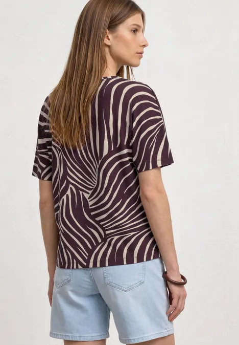 Kurzarm Shirt mit Rundhals und Print rustic rouge Eine Frau von hinten mit gestreiftem Zebra-Muster-Shirt und hellen Jeans-Shorts, braune glatte Haare.