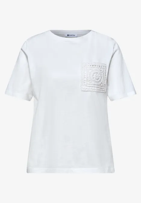 Weißes T-Shirt mit Rundhalsausschnitt und aufgesetzter Spitze an der Brusttasche.