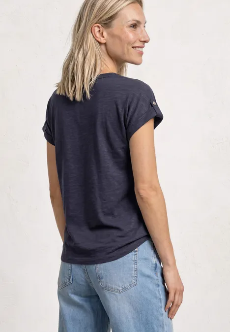 T-Shirt mit Split Neck und Knopfdetails shadowed navy Eine Frau von hinten, trägt ein dunkelblaues T-Shirt und helle Jeans, steht vor hellem Hintergrund.