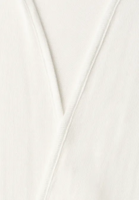 Close-up van een crèmewitte stof met een V-vormige naad.