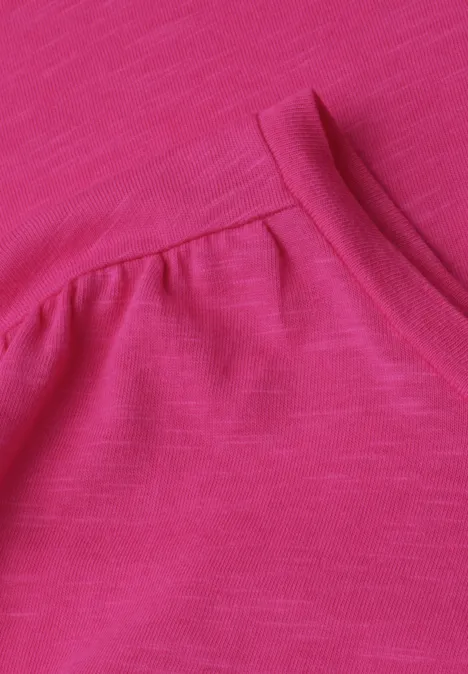 Close-up van een felroze T-shirt met ronde hals en subtiele plooitjes