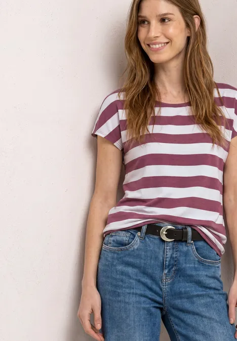 Vrouw met paars-wit gestreept T-shirt en een spijkerbroek met riem.